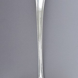 May include: A silver ladle with a decorative handle and a round bowl. The handle has a scalloped design and a beaded edge.