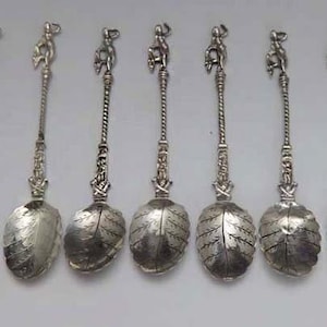 Puede incluir: Conjunto de diez cucharaditas de plata con mangos adornados y cuencos en forma de hoja.