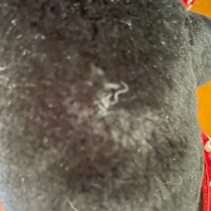 Pu&ograve; includere: Primo piano di una superficie di tessuto nero con un filo o un segno bianco. Il tessuto ha una consistenza pelosa.