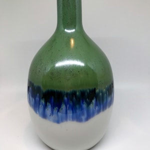 May include: A green, blue, and white ceramic vase with a rounded body and a narrow neck.