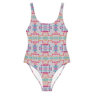 May include: A one-piece swimsuit with a geometric pattern in shades of pink, blue, orange, and yellow on a white background.