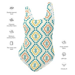 May include: A one-piece swimsuit with a geometric pattern in shades of blue, orange, and yellow on a cream background. The swimsuit has a scoop neck and a cheeky fit.