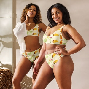 May include: Two-piece bikini set with a light yellow background and a repeating pattern of tacos, lime slices, margarita glasses, and tequila bottles. The bikini top is a scoop neck style, and the bottoms are high-waisted.