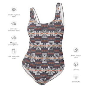 May include: A black swimsuit with a geometric pattern in orange, white, and grey. The swimsuit has a scoop neck, thin straps, and a cheeky fit. It is made from a 4-way stretch fabric that is moisture-wicking and has a tear-away care label.