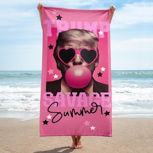 May include: Pink beach towel featuring a portrait of a man wearing heart-shaped sunglasses and blowing a bubblegum bubble. The towel has the words "TRUMP" and "SAVAGE Summer" in pink and white, with star accents.