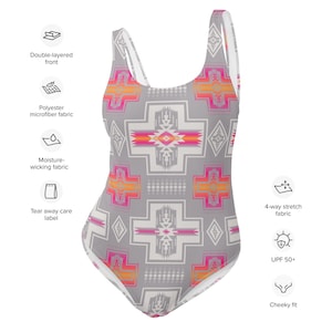 May include: A grey, pink and orange geometric patterned swimsuit with a cheeky fit. The swimsuit has a double-layered front, is made of polyester microfiber fabric, and is moisture-wicking. It also has a tear-away care label, 4-way stretch fabric, and UPF 50+ sun protection.