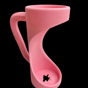 May include: A pink, uniquely shaped mug with a curved handle and a base with a star-shaped cutout. The mug's design features a continuous, flowing form, and it is set against a black background.