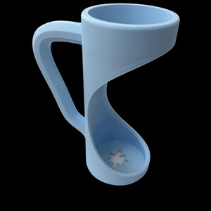 May include: A light blue mug with a unique, curved design. The handle is integrated into the body, creating a continuous, flowing form. The base features a white star design. The mug is set against a black background.