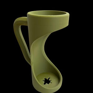 May include: A unique olive green mug with a distinctive, flowing design. The handle curves gracefully into the base, which features a star-shaped cutout. The mug's form is modern and sculptural, set against a black background.