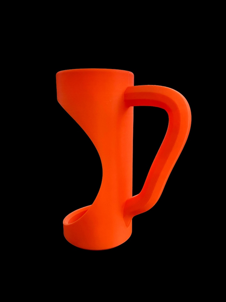 May include: Bright orange mug with a unique, curved design. The mug features a wide, flared base that tapers upwards to a narrower midsection, then widens again at the top. The handle is a thick, rectangular shape. The mug is set against a black background.