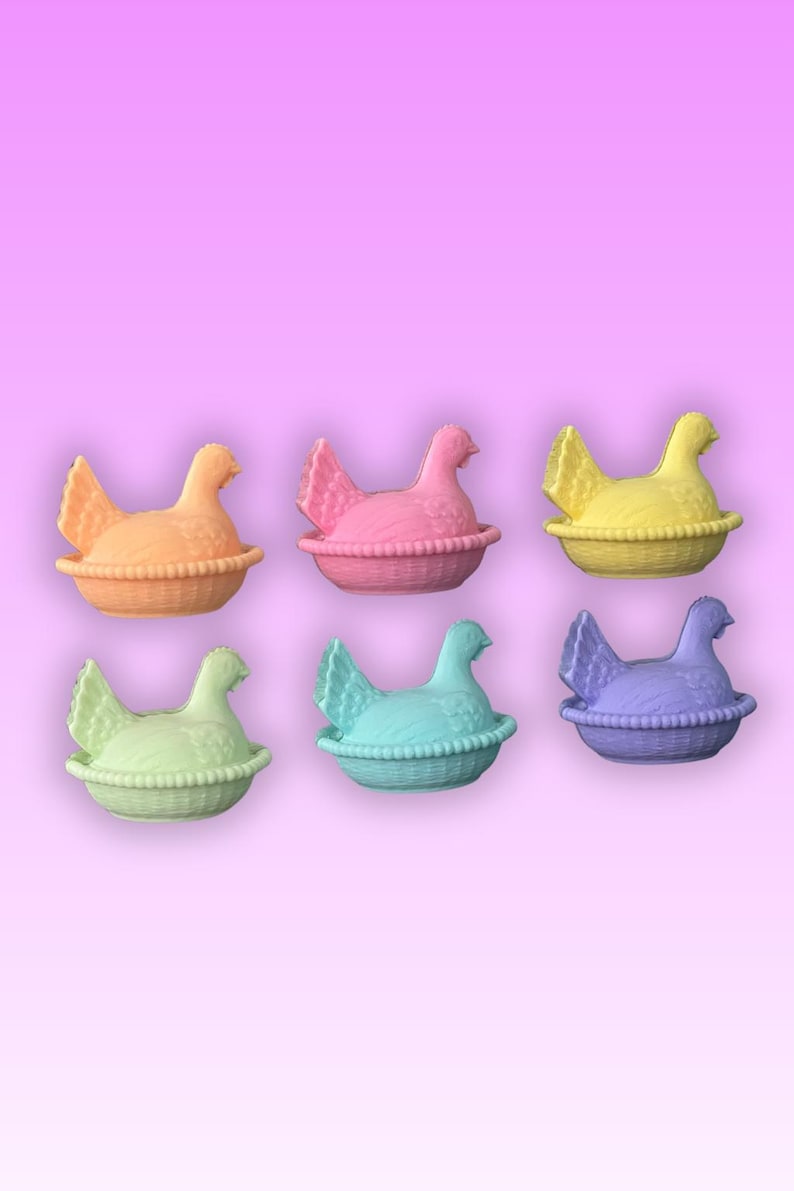 May include: Six colourful hen-shaped containers in orange, pink, yellow, green, blue, and purple. Each hen sits in a basket-like base. The background is a gradient of pink and purple.