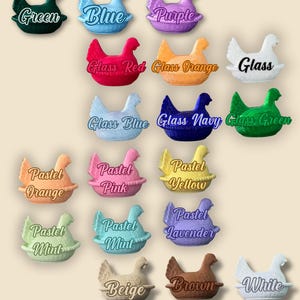 May include: A selection of hen-shaped ornaments in a variety of colours, such as red, orange, yellow, green, blue, and purple. Each hen is labelled with its colour name. Additional colours include glass, pastel, beige, brown, white, navy, grey, and black.