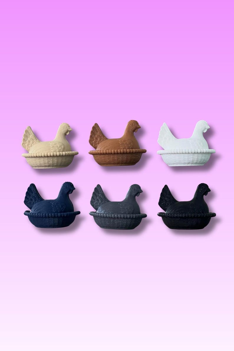 May include: Six ceramic hen ornaments in cream, brown, white, navy blue, grey, and black. Each hen sits in a woven basket. The background is a gradient of pink and purple.