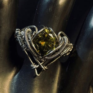 May include: A silver wire wrapped ring with a large, green, faceted gemstone.