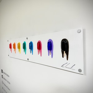 May include: A colourful abstract art piece featuring a row of popsicles in various colours, including red, orange, yellow, green, blue, purple, and black. The popsicles are dripping with melted ice cream, creating a vibrant and playful design. The artwork is signed by the artist.