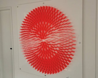 May include: A red and white geometric art piece made of paper squares arranged in a circular pattern. The piece is mounted on a white background and signed "Lhunk" in the bottom right corner.
