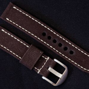 May include: Two brown canvas watch straps with white stitching. The straps have a buckle and are designed for a watch.