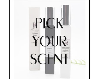 May include: Three glass bottles of perfume spray with white labels. The labels have black text that reads "All about Patchouli" and the names of the scents: "Perfume Spray", "Patchouli Amber", and "Patchouli Sandalwood". The text "PICK YOUR SCENT" is superimposed on the image.
