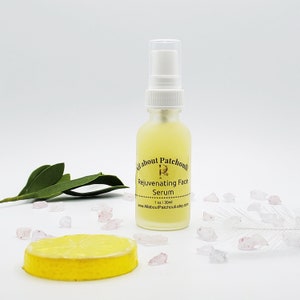 May include: A clear glass bottle with a white pump top filled with a yellow liquid. The bottle has a gold label that reads "All about Patchouli Rejuvenating Face Serum 1 oz / 30ml www.AllAboutPatchouli.etsy.com".