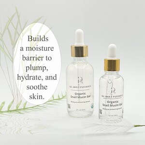 May include: Two clear glass bottles of Organic Snail Mucin Gel with gold-colored caps and white droppers. The bottles are labeled "ALL ABOUT PATCHOULI" and "Moisture enhancing Serum." Text on the image reads "Builds a moisture barrier to plump, hydrate, and soothe skin."