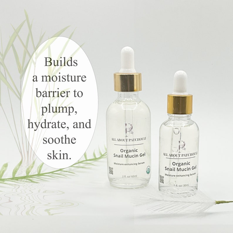 May include: Two clear glass bottles of Organic Snail Mucin Gel with gold-colored caps and white droppers. The bottles are labeled "ALL ABOUT PATCHOULI" and "Moisture enhancing Serum." Text on the image reads "Builds a moisture barrier to plump, hydrate, and soothe skin."