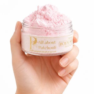 May include: A clear plastic jar filled with light pink, whipped body polish. The label features gold text reading All about Patchouli, the URL allaboutpatchouli.etsy.com, and the words BODY POLISH. The product has a textured, airy consistency.