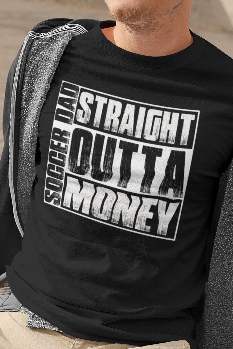 May include: Black t-shirt with a white graphic that says "Soccer Dad Straight Outta Money".
