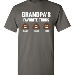 May include: A dark gray t-shirt with the text "Grandpa's Favorite Turds" in white. Three cartoon poop emojis with smiling faces are below the text, each with the word "NAME" underneath.