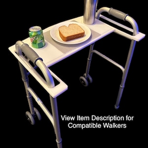 May include: A white tray table with a gray metal frame and wheels. The tray has a gray placemat and a sandwich on a white plate. A can of soda and a silver travel mug are also on the tray.  View Item Description for Compatible Walkers.