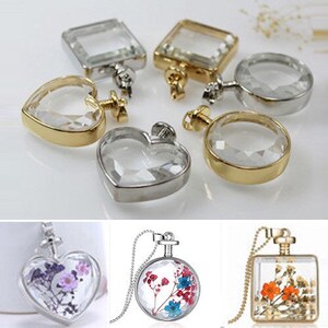 May include: Assortment of clear glass pendant charms with gold and silver metal frames. The charms are shaped like hearts, squares, and circles. Some of the charms have dried flowers inside.