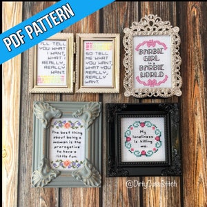 Puede incluir: Una colección de patrones de punto de cruz enmarcados con varias citas y frases. Los marcos son de diferentes estilos y colores, incluyendo dorado, plateado, gris y negro. El texto incluye "Barbie Girl" y "Mi soledad me está matando."