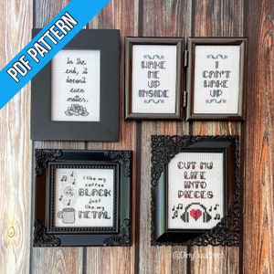Peut inclure: Quatre broderies au point de croix encadrées avec des cadres noirs. Les motifs comprennent : "In the end, it doesn't even matter." avec un motif floral, "Wake me up inside", "I can't wake up", et "Cut my life into pieces" avec un cœur brisé et des notes de musique.