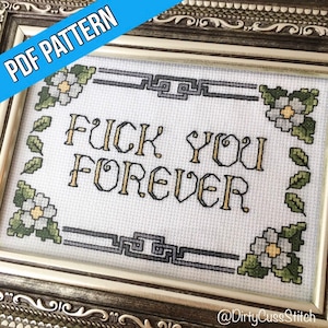 Peut inclure: Un motif de point de croix représentant la phrase "F*CK YOU FOREVER" dans une police de caractères de style vintage, entouré d'une bordure décorative de fleurs et de feuilles. Le motif est encadré dans un cadre doré.