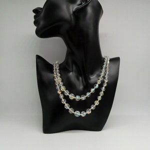 May include: A double strand iridescent crystal bead necklace on a black mannequin bust.