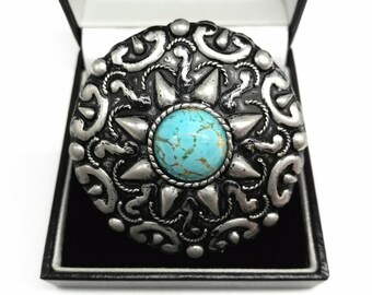 May include: A silver-toned belt buckle with an ornate design and a turquoise stone in the center.