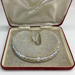 May include: A clear crystal necklace with iridescent beads in a red velvet lined box with the label "Rosita Grosvenor" on the lid.