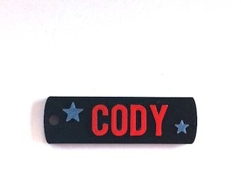May include: Black rectangular tag with a red "CODY" inscription and two blue stars on either side.