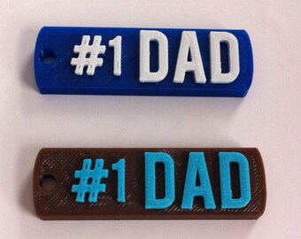 May include: Two keychains with the text "#1 DAD" in white and blue lettering on a blue and brown background.