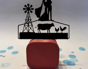 May include: Black silhouette wedding cake topper featuring a kissing couple with a heart-shaped cutout, a windmill, a cow, and two chickens. The topper is placed on a red square base with blue and white confetti.