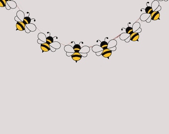 May include: A string of cartoon bees with black and yellow bodies and white wings. The bees are strung together on a thin, light pink string, creating a garland effect. The background is a solid, light gray color.