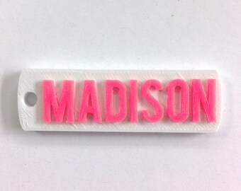 May include: White plastic keychain with the name "MADISON" in pink letters.