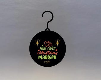 May include: Black round Christmas ornament with a hook. The ornament features the text "OUR FIRST Christmas MARRIED 2025" in a colorful design with hearts and stars.