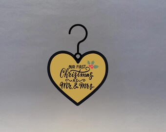 May include: A heart-shaped Christmas ornament with a gold center and black border. The ornament has a black hook and features the text "OUR FIRST Christmas as Mr. & Mrs." in elegant script, with holly accents.