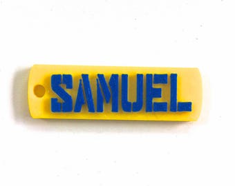 May include: A yellow plastic keychain with the name "SAMUEL" printed in blue.