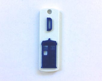 May include: White plastic tag with a blue silhouette of the TARDIS and the letter "D" on it.