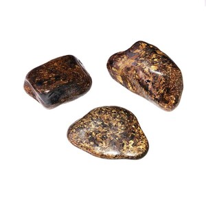 Peut inclure: Trois pierres polies et roulées avec une base brun foncé et des éclats métalliques dorés irréguliers répartis sur leurs surfaces lisses et arrondies. Chaque pierre présente une forme organique unique et une finition brillante.