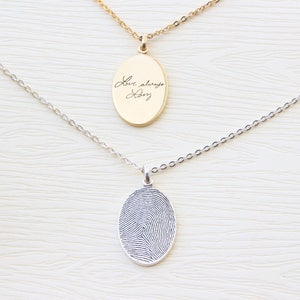 May include: Two silver necklaces with oval pendants. One pendant has a fingerprint design, the other has the handwritten text "Love always, Dadz".