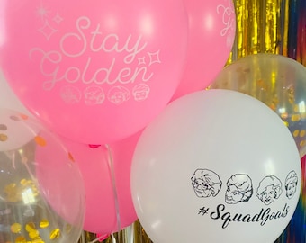 May include: Pink and white balloons with gold confetti. One balloon says "Stay Golden" with a row of small faces. Another balloon says "#SquadGoals" with four faces.