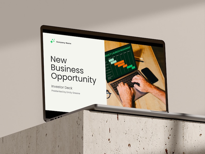 May include: A laptop screen displaying a presentation titled "New Business Opportunity" with a green and orange product launch roadmap chart. The laptop is on a wooden table with a person's hands typing on the keyboard.