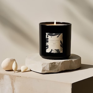 May include: A black candle with a white label that says "Elderflower" and "12 oz Soy Candle" on a light gray stone surface.